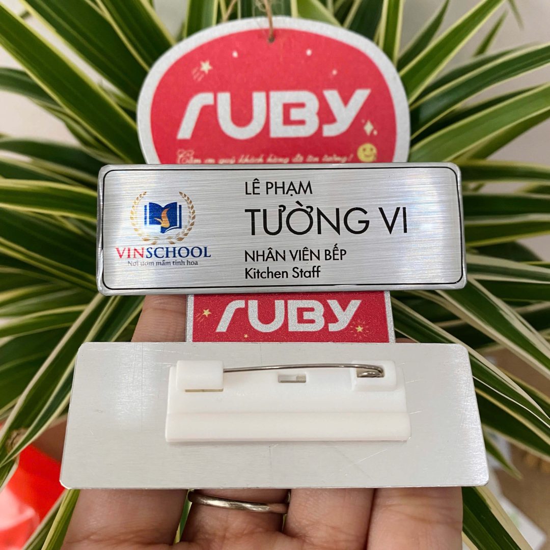 Bảng tên nhân viên kim cài bằng nhôm xước bạc cho trường học, in logo Vinschool và tên–chức danh, mặt sau gắn kim cài an toàn.