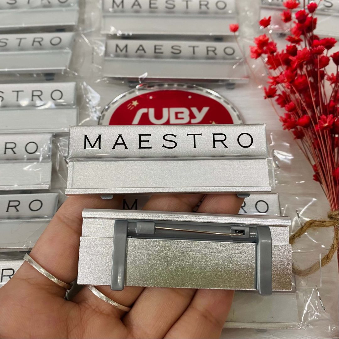 Bảng tên thay tên MAESTRO bằng nhôm bạc, in chữ đen, mặt sau có ghim gài chắc chắn.