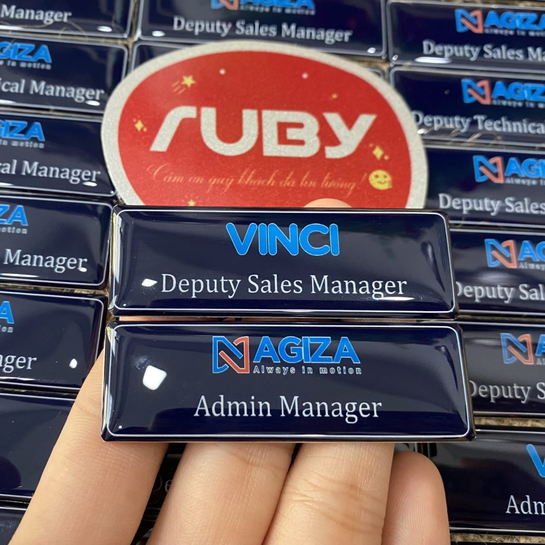 Bảng tên nhân viên nhôm nền xanh đen, in logo công ty AGIZA và VINCI, chức danh Deputy Sales Manager, Admin Manager, mặt sau có nam châm.