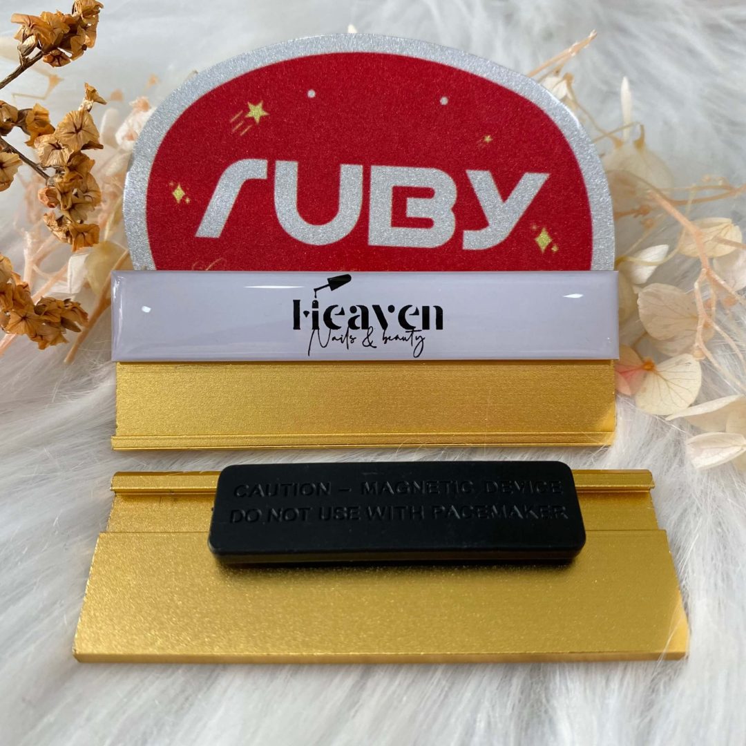 Bảng tên nhân viên nền trắng in logo Heaven Nails & Beauty, phôi bảng tên vàng sang trọng, gắn nam châm phía sau.