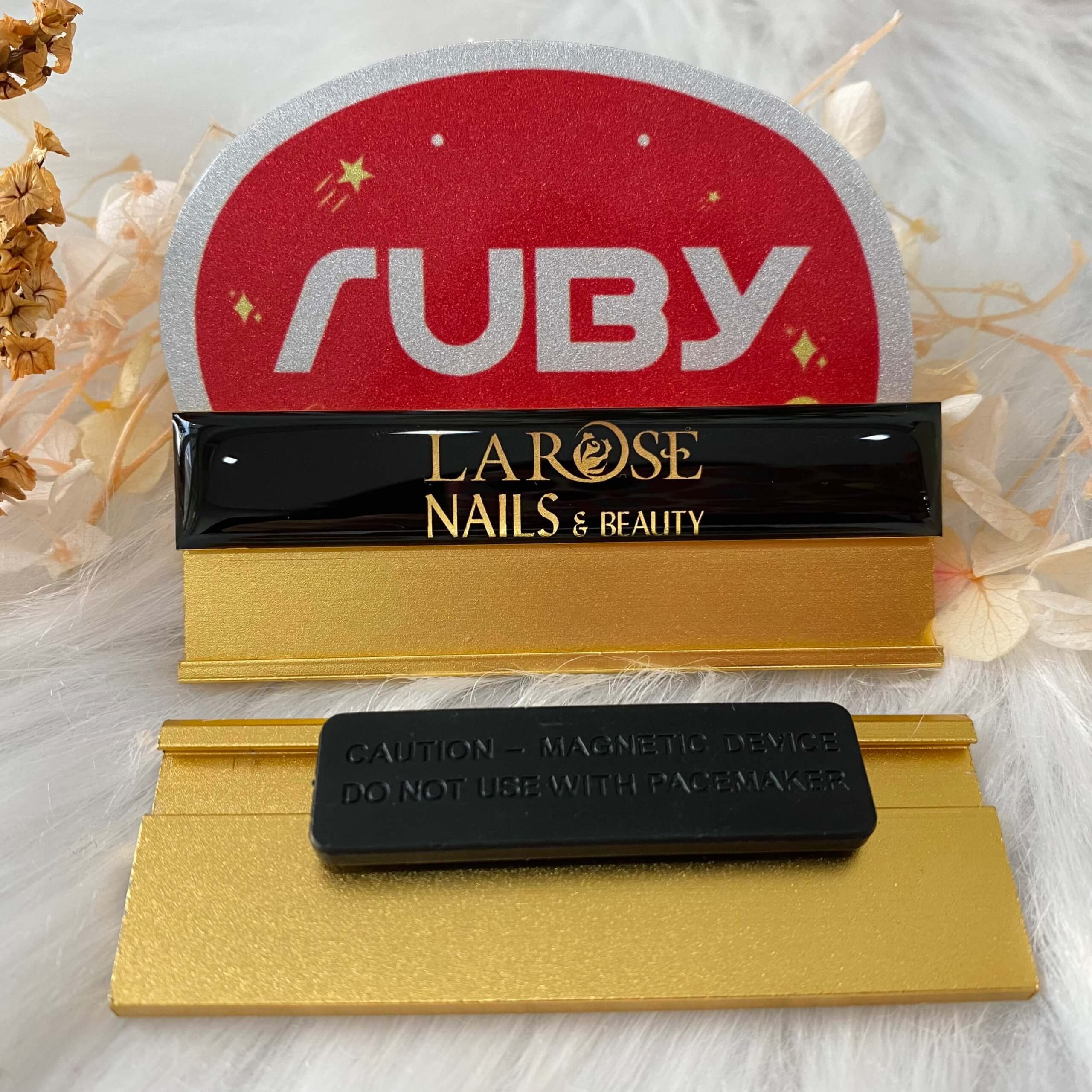 Bảng tên nhân viên màu đen in logo vàng La Rose Nails & Beauty, phôi vàng, gắn nam châm tiện dụng.