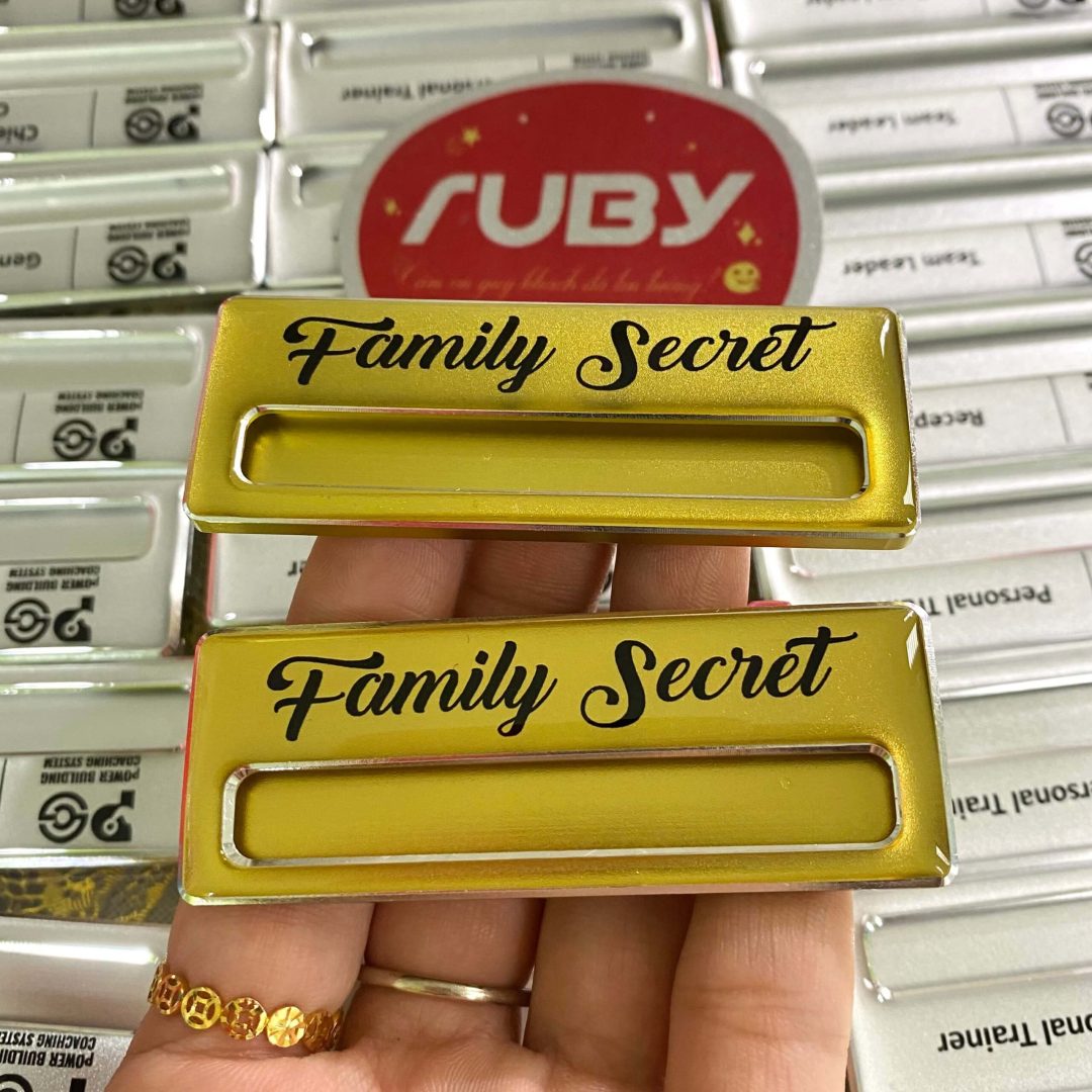 Bảng tên Family Secret, nền vàng, in chữ đen nổi bật, kiểu chữ uốn lượn sang trọng.