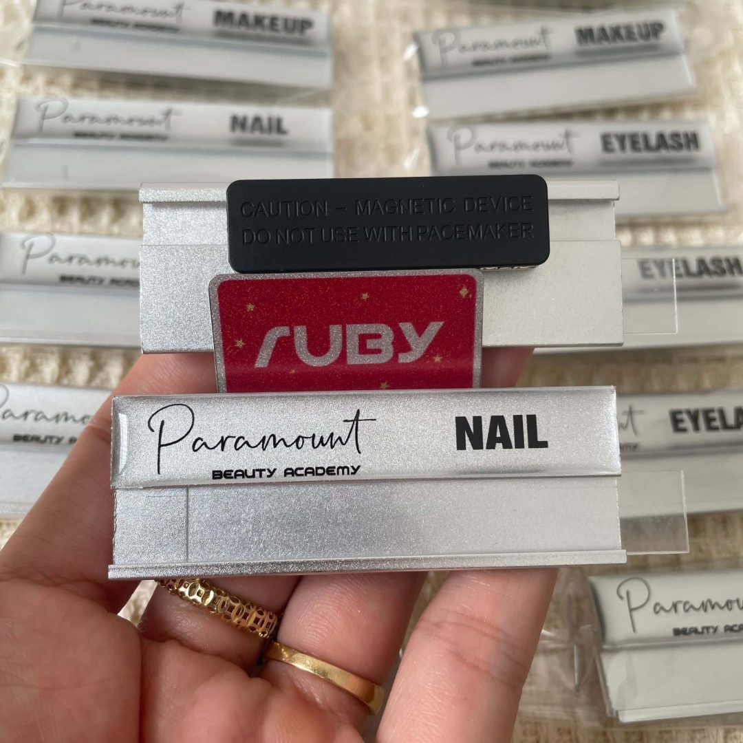 Bảng tên nhân viên Paramount Beauty Academy, nền bạc sang trọng, in logo và chuyên ngành Nail, gắn nam châm.