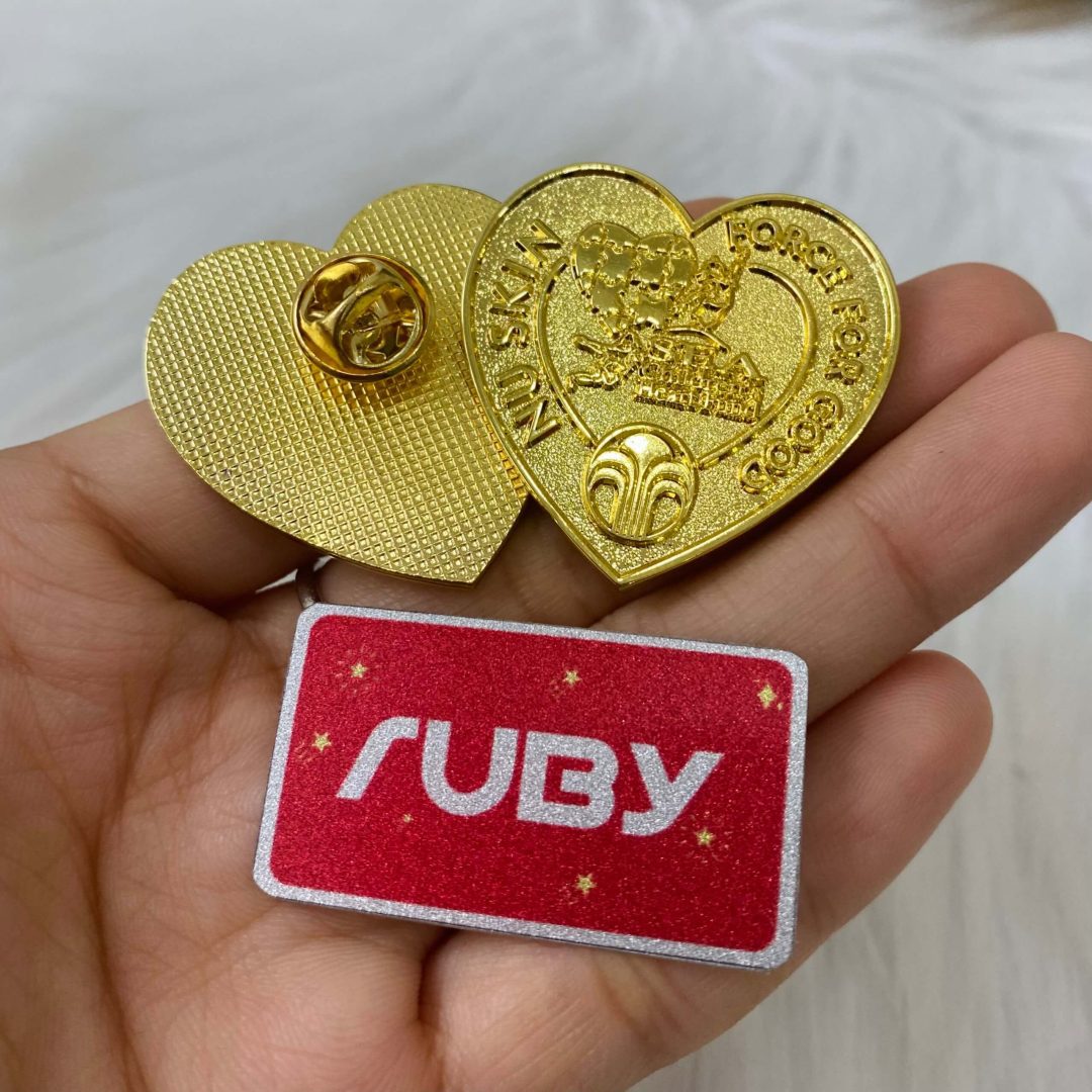 Huy hiệu trái tim NU SKIN mạ vàng, mặt trước ăn mòn logo và dòng chữ Force For Good, chốt gài tròn