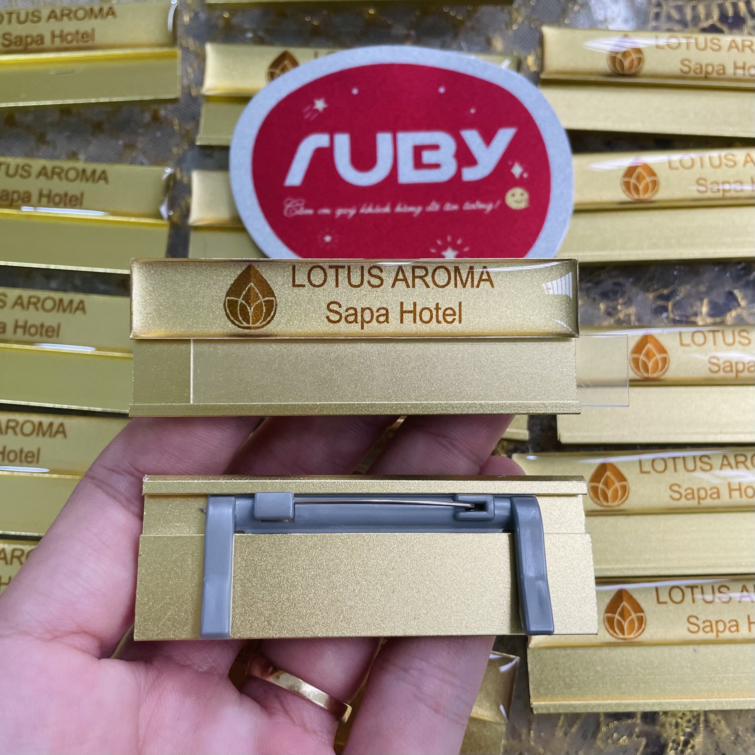 Bảng tên kim loại phủ keo epoxy Lotus Aroma Sapa Hotel gắn ghim cài.