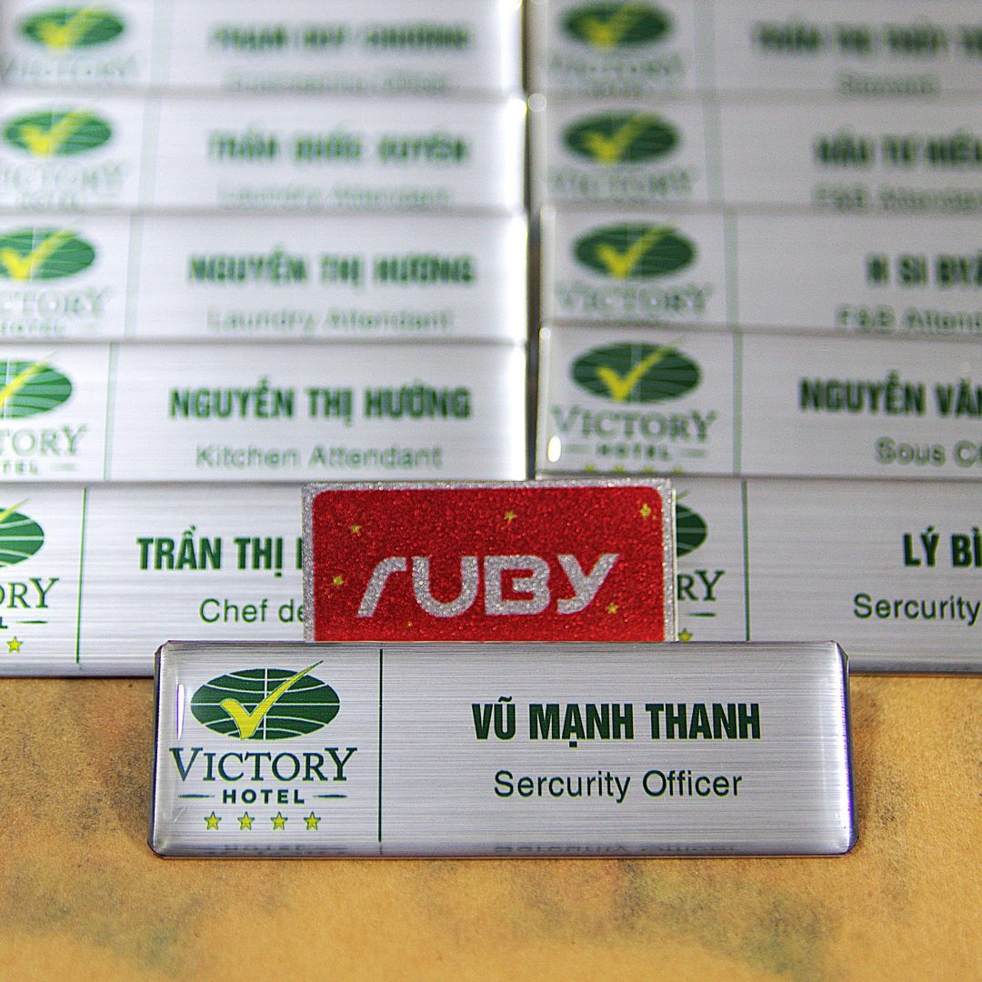 Bảng tên nhân viên khách sạn in cố định kim loại bạc xước, phủ keo epoxy bảo vệ bề mặt chống trầy.