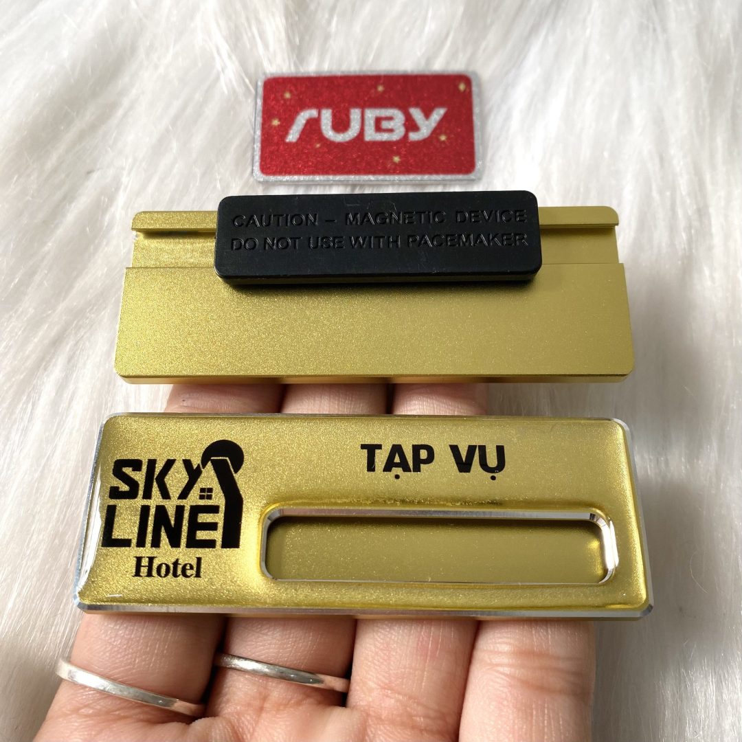 Bảng tên nhân viên bộ phận Tạp vụ Sky Line Hotel mạ vàng nhũ, có khe thay tên và mặt sau đính nam châm hít cao cấp.