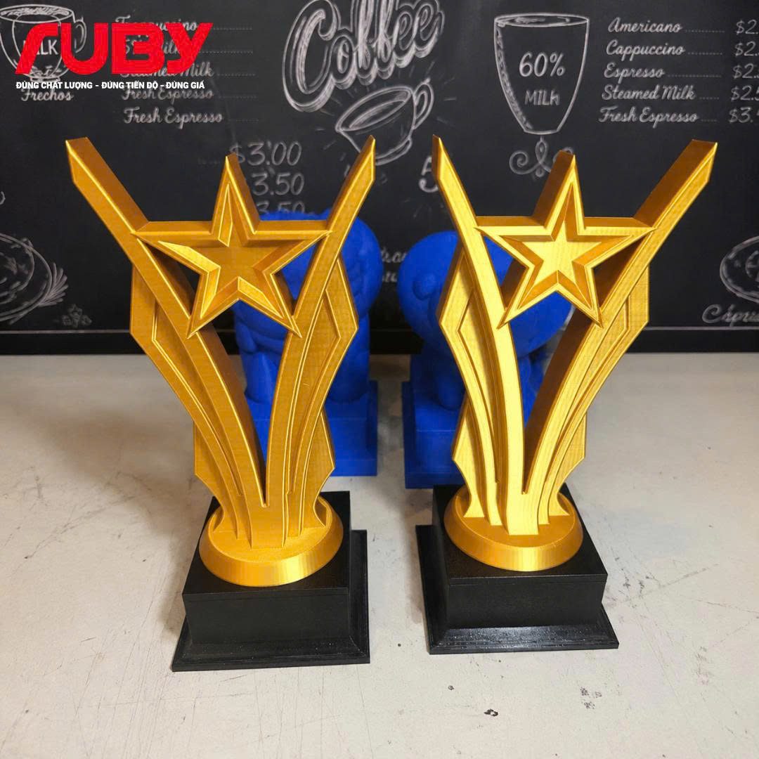 Cúp vinh danh ngôi sao vàng in 3D đế đen chụp chính diện, sản phẩm kỷ niệm chương cao cấp của thương hiệu Ruby.